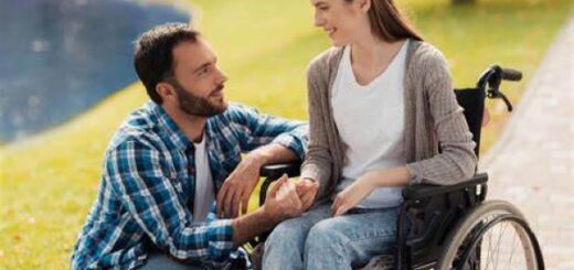 Photo d'une femme et fauteuil roulant et d'un homme acroupie à son niveau.