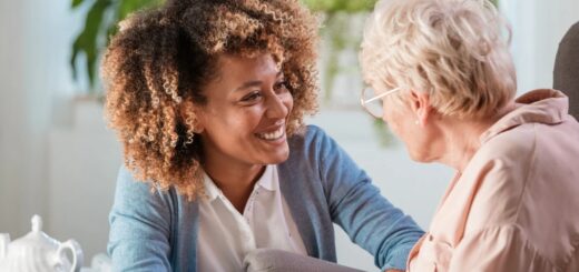 Photo d'une personne âgée assise et d'une jeune femme accroupie à son niveau dans une attitude chaleureuse.