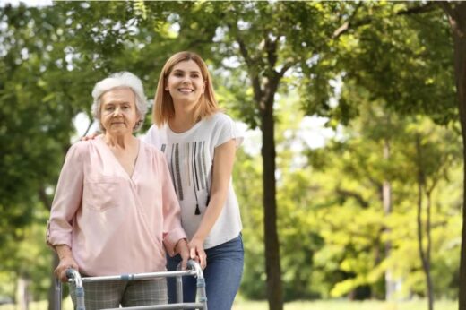 Photo d'une personne âgée avec un déambulateur et une jeune femme à sa droite.