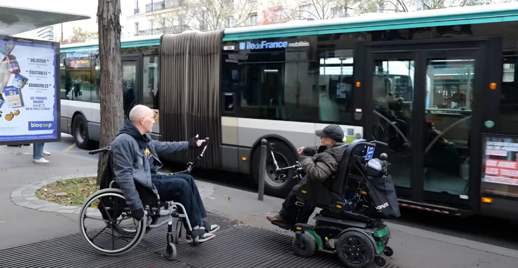 Deux personne sur fauteuil roulant et un bus.