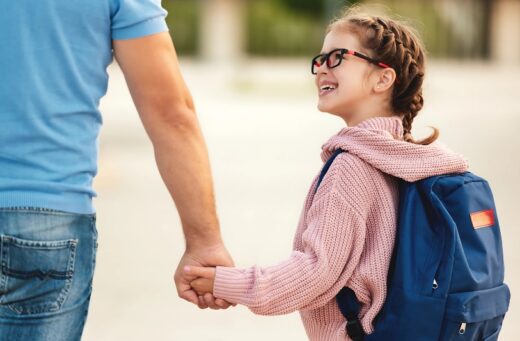 Photo d'une fille et son père, main dans la main.